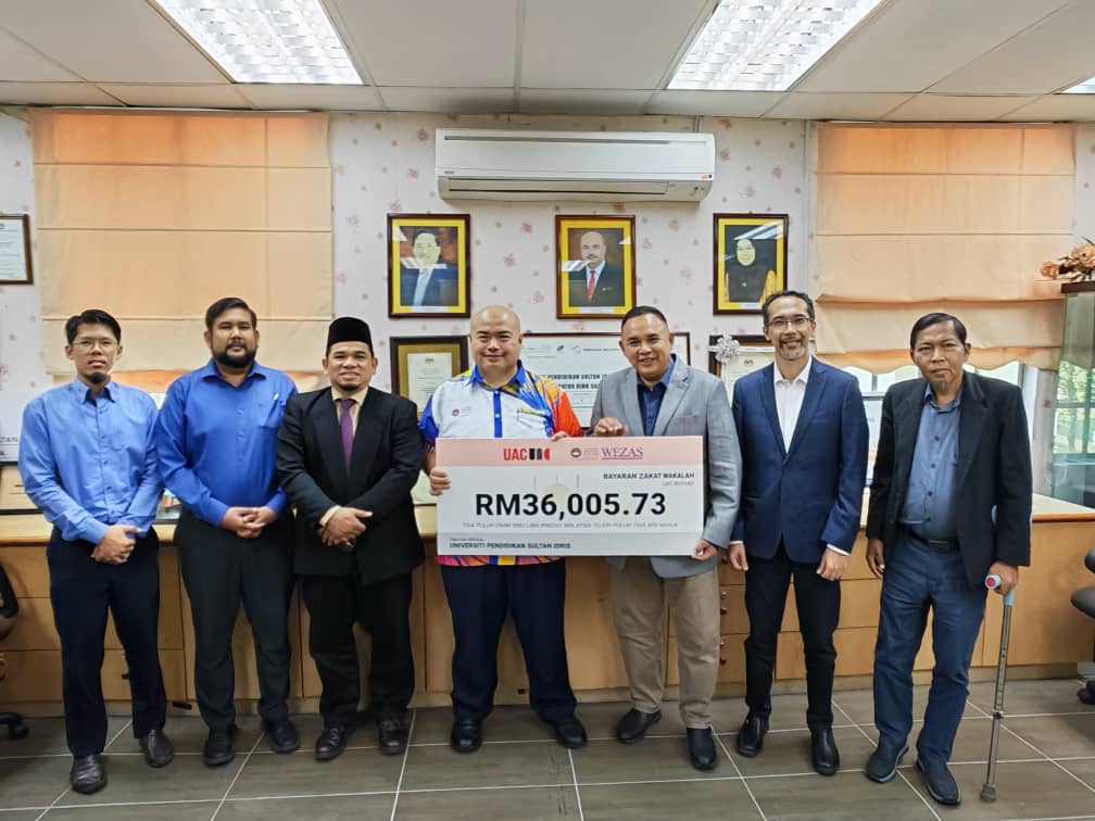 Mohamad Najib (empat dari kiri) bergambar kenangan bersama kakitangan UPSI dan UAC Berhad sambil memegang replika cek dalam satu majlis ringkas di Bangunan Canselori UPSI.