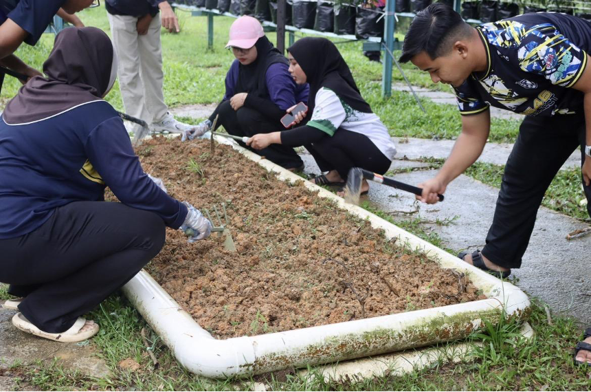 Pelajar terlibat sedang menggembur batas untuk persediaan menanam biji benih.