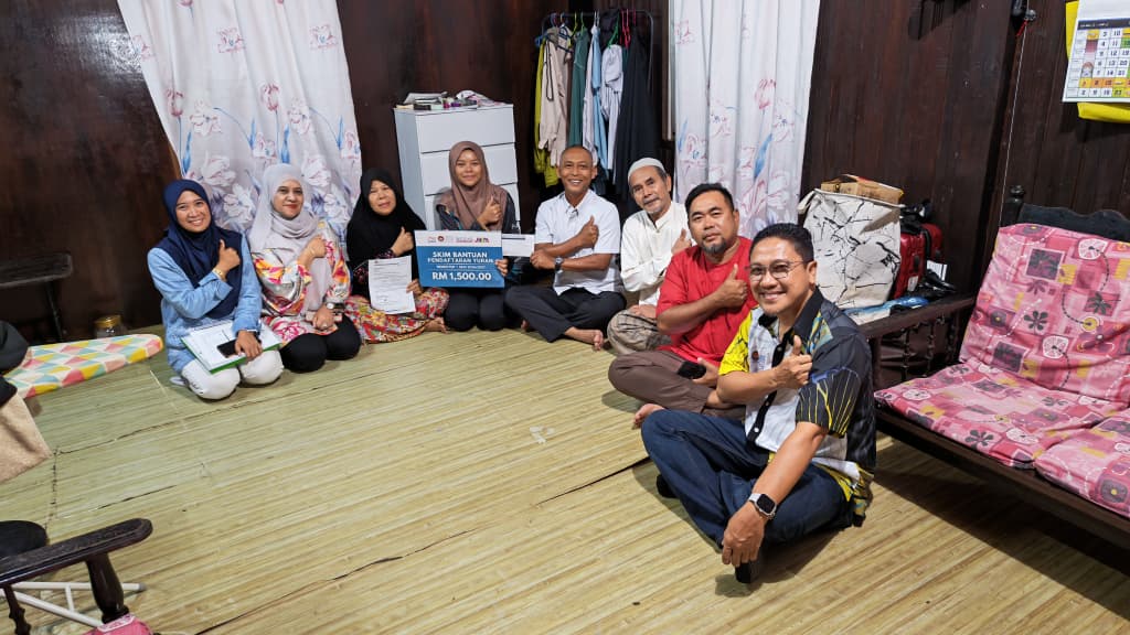 Dr Norkhalid (empat dari kanan) bergambar ketika menyampaikan Skim Bantuan Pendaftaran Yuran bernilai RM 1,500.00 kepada Siti Nor Ba’iyah (empat dari kiri) pada program ziarah kebajikan di Kampung Hutan Nangka, Jerteh.